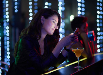 俱乐部微笑年轻的女人阅读文本消息坐着酒吧夜总会