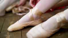 关闭芭蕾舞 演员改变鞋子特殊的芭蕾舞鞋子尖端鞋子花边芭蕾舞丝带木地板上芭蕾舞类