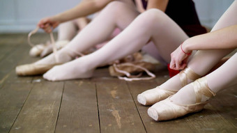 关闭芭蕾舞 演员改变鞋子特殊的芭蕾舞鞋子尖端鞋子花边芭蕾舞丝带木地板上芭蕾舞类