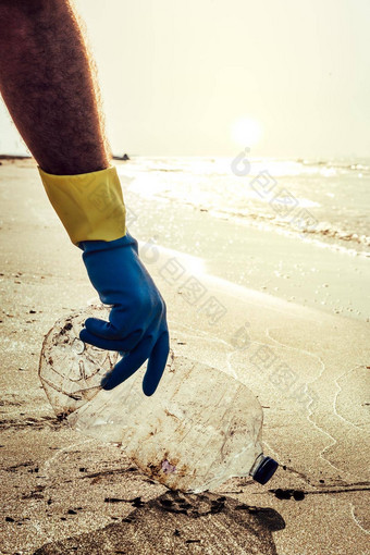 男人。手挑选塑料污染海滩