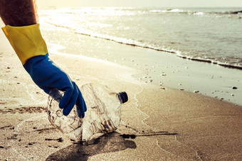 男人。手挑选塑料污染海
