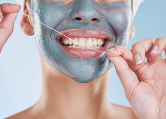 牙科脸面具女人用牙线清洁牙齿牙齿健康的强大的牙齿工作室肖像蓝色的背景女孩清洁口脸皮肤美护理口服卫生