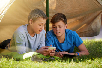 检查伙计年轻的男孩显示朋友手机他们野营