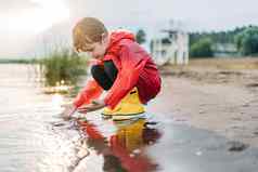 男孩红色的雨衣黄色的橡胶靴子玩水海滩学校孩子防水外套触碰水海孩子有趣的波海岸