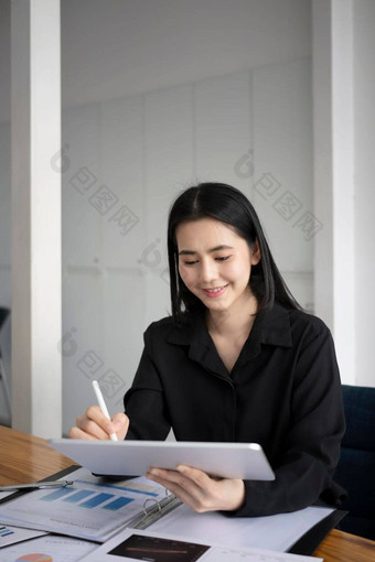 微笑亚洲女商人坐着工作场所检查信息数字平板<strong>电脑</strong>