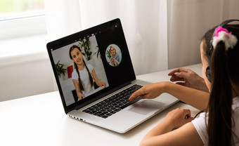 自主学习年轻的女孩学习在线类学校老师数字远程互联网会议由于冠状病毒流感大流行孩子电脑写作请注意妈妈。