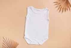 白色婴儿紧身衣裤模型标志文本设计米色背景棕榈叶子前视图