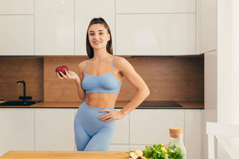 肖像美丽的年轻的体育健身女人营养学家持有苹果新鲜的水果蔬菜首页厨房相机微笑