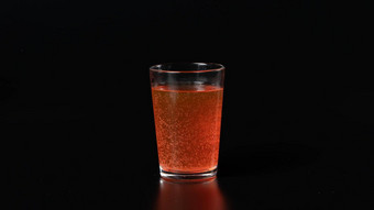 玻璃碳酸橙色水黑色的背景泡沫喝鸡尾酒