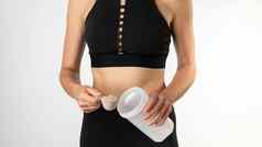 女人运动服装测量勺子蛋白质把体育营养瓶