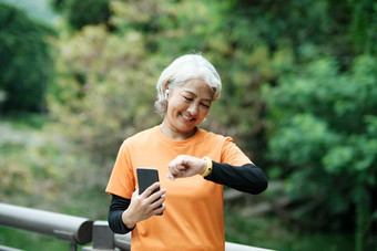 快乐运动高级女人检查智能手表公园