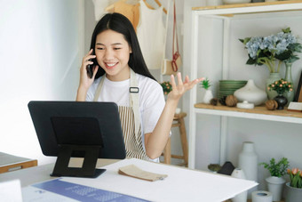 年轻的亚洲企业家坐着陶瓷产品销售房间工作移动PC