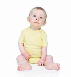 穿着阳光明媚的一天可爱的婴儿男孩坐着地板上白色背景