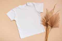 白色婴儿t恤前视图模型标志设计米色背景平躺孩子衣服棕榈叶子
