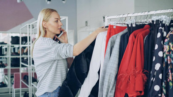 女客户慢慢地时尚衣服悬挂器宽敞的商店客户移动衣服鞋子背景