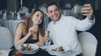 有吸引力的爱的夫妇采取自拍香槟眼镜智能手机浪漫的晚餐餐厅微笑摆姿势相机