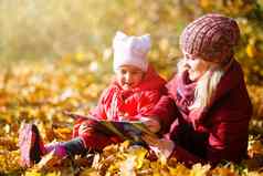 可爱的女孩阅读书在户外秋天