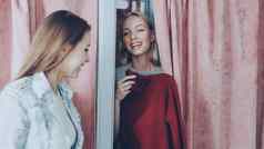 年轻的女人一半隐藏的窗帘拟合房间获取红色的针织衣服女朋友把衣服画窗帘