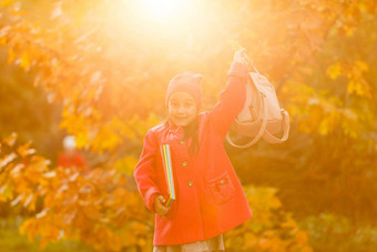 可爱的女孩运行秋天公园踢下降叶子女学生背包学校概念秋天学校研究教育童年回来学校