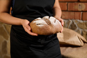 裁剪视图家庭主妇贝克黑色的厨师围裙持有面包新鲜的烤温暖的粮食小麦面包手