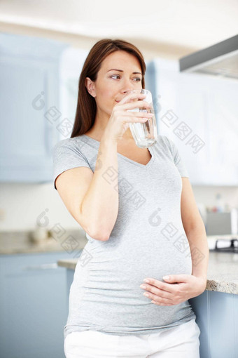 有责任心的健康婴儿微笑怀孕了女人喝水厨房深思熟虑的
