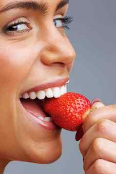 快乐的年轻的女人吃新鲜的草莓细节拍摄快乐的年轻的女人吃新鲜的草莓
