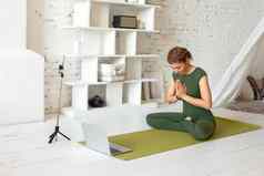 美丽的女人绿色体育连身裤明亮的房间广播在线执行瑜伽锻炼