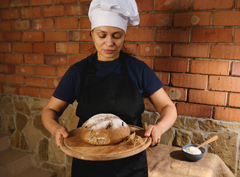 迷人的女贝克黑色的酋长围裙白色帽持有木董事会新鲜的自制的酵母黑麦面包