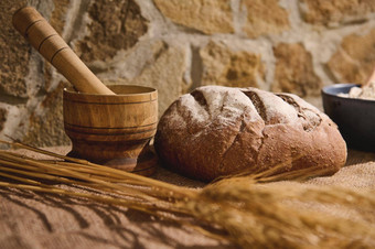 传统的粮食面包亚麻桌布木砂浆小麦小穗模糊前景