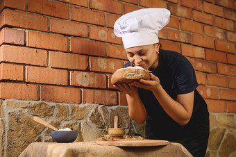 迷人的女人贝克嗅探面包传统的自制的粮食小麦面包烤手工家庭面包店