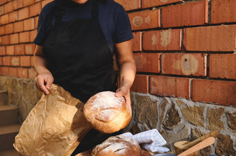 裁剪视图贝克穿着黑色的持有粮食传统的面包把生态纸袋