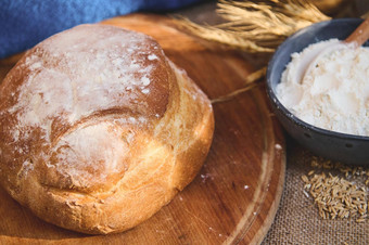 面包酵母面包木董事会模糊蓝色的陶瓷碗白色面粉小穗小麦
