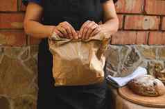 裁剪视图女贝克工匠面包店商店工人持有生态纸袋包装新鲜的传统的面包