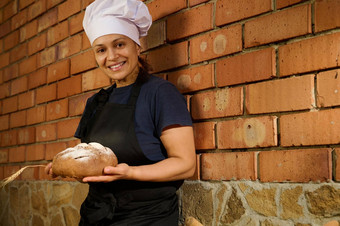 美丽的女贝克摆姿势传统的自制的酵母小麦面包红色的砖墙背景