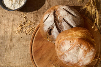 前视图饼新鲜的自制的面包木董事会分散谷物小麦小穗麻布