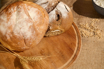 各种饼新鲜烤面包木董事会分散谷物小麦耳朵粗麻布桌布