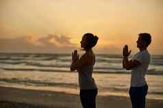 实现健康幸福瑜伽夫妇瑜伽海滩日落