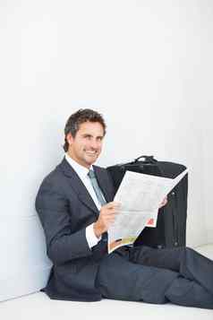 业务男人。微笑阅读报纸聪明的微笑业务男人。坐着墙阅读报纸给温暖的微笑