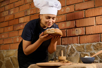 拉美裔女贝克嗅探面包传统的自制的新鲜的烤粮食小麦面包arisanal家庭面包店