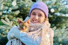 年轻的女雪天气猫相机户外圣诞节树