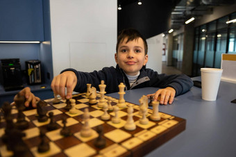 聪明的高加索人男孩持有国际象棋一块移动棋盘国际象棋策略教训intelectual爱好