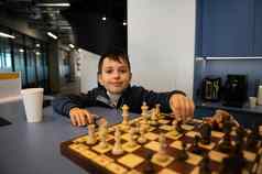 可爱的知识聪明的高加索人十几岁的学校男孩可爱的微笑相机玩国际象棋朋友