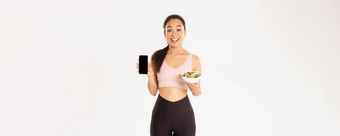体育运动<strong>幸福</strong>活跃的生活方式概念微笑苗条的可爱的亚洲健身女孩健身房教练显示沙拉智能手机屏幕推荐下载饮食跟踪器卡<strong>路</strong>里提醒