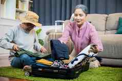 亚洲浪漫的退休夫妇包装衣服旅行袋手提箱地板上首页