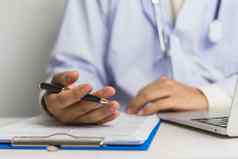 医生手持有笔写文书工作文档病人治疗剪贴板业务健康护理概念