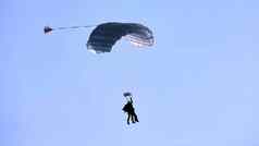他降落白色降落伞树冠蓝色的天空白色云特写镜头