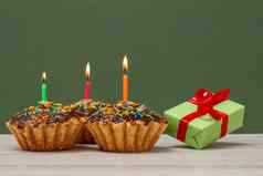 生日纸杯蛋糕燃烧节日蜡烛礼物盒子绿色背景