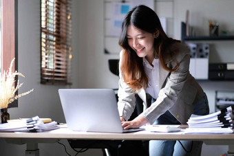快乐年轻的亚洲女商人站计算器移动PC电脑办公室