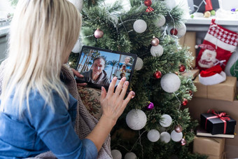 年轻的女人背景圣诞节树礼物平板电脑视频调用视频闲谈，聊天朋友家庭圣诞节在线假期保持首页假期
