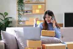 快乐年轻的亚洲女人企业家微笑销售成功检查订单在线购物商店智能手机首页办公室概念商人业务在线电子商务